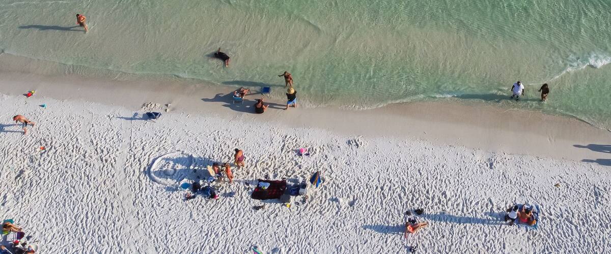 A crowded beach with people sunbathing and swimming.