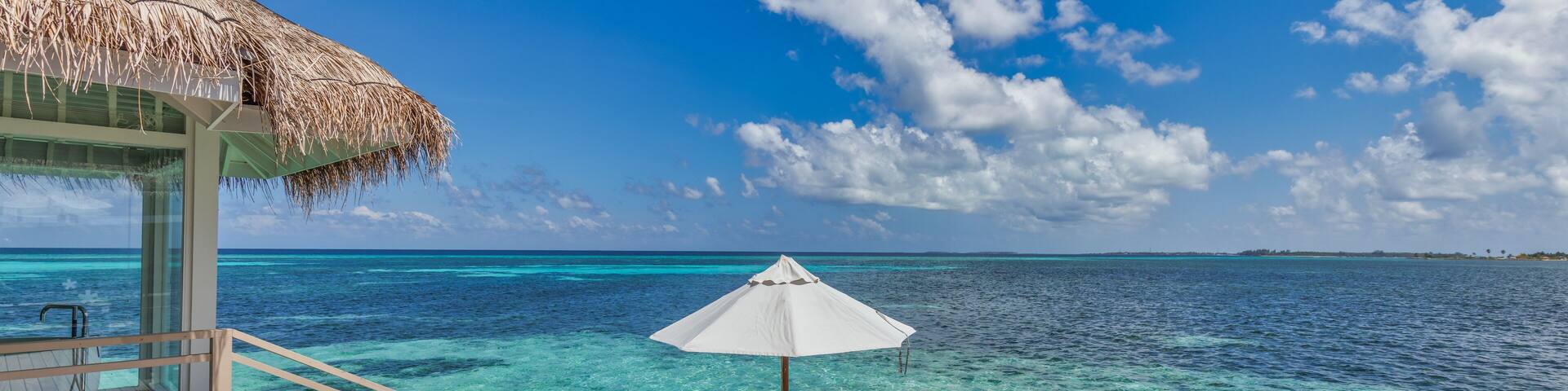 Stunning sunny sky clouds sea on horizon of turquoise ocean bay. Lagoon landscape in Maldives. Luxury travel panorama, infinity pool leisure couple villa, private destination tourism. Chairs umbrella