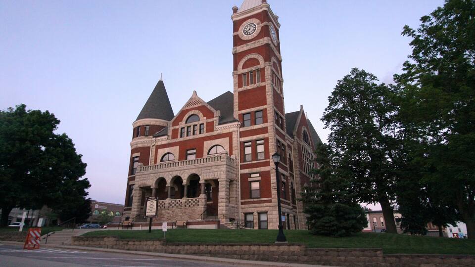 A large, historic building with a clock tower, arched windows, and a prominent entrance.