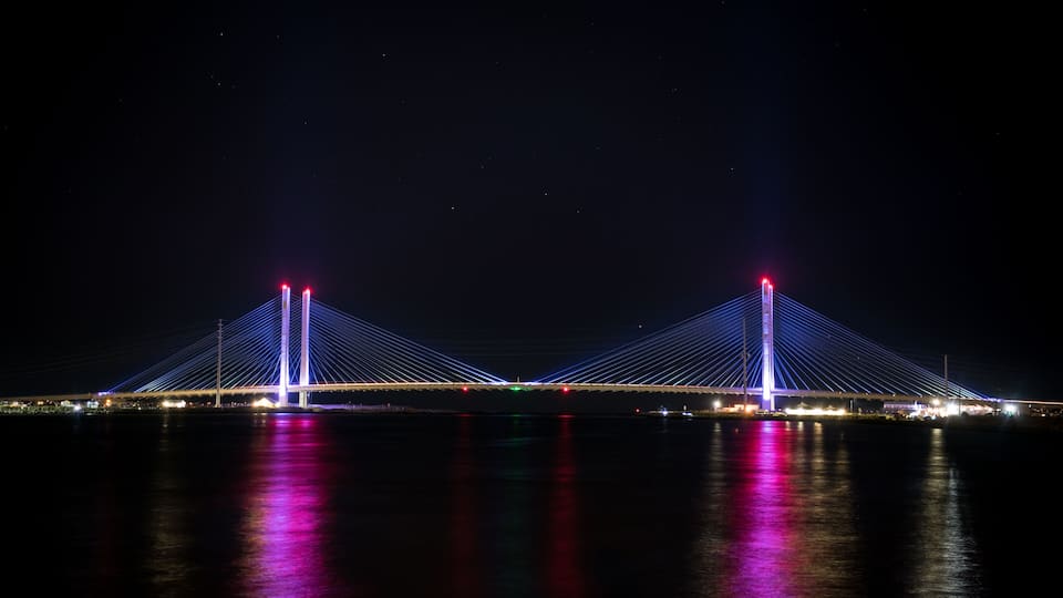 A bridge with two towers and cables, illuminated at night.