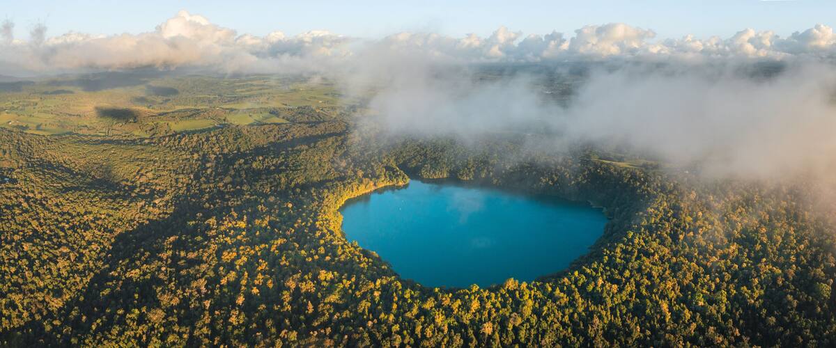A lake surrounded by forested hills and clouds.