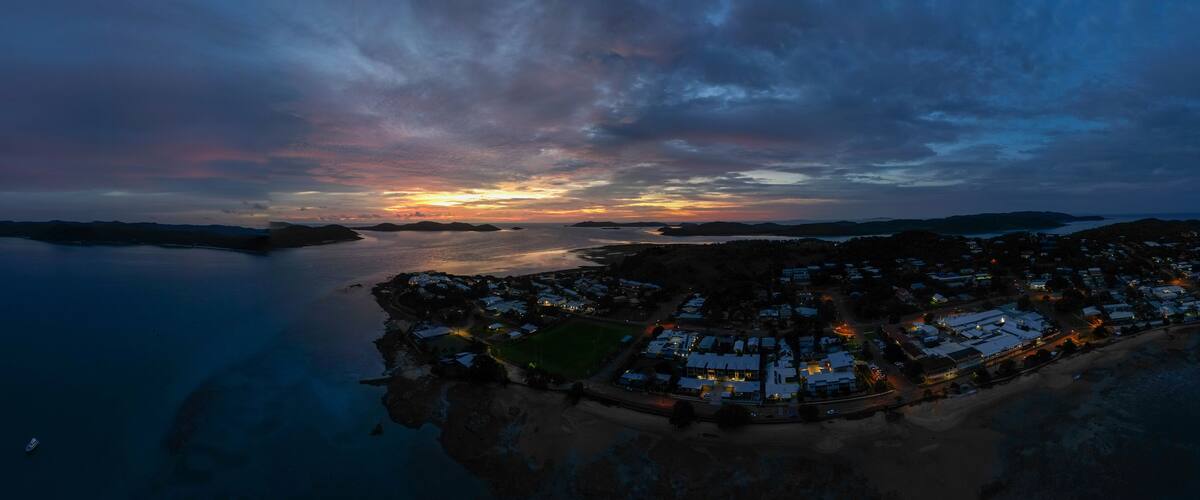 A coastal town at dusk with a sunset over the water.