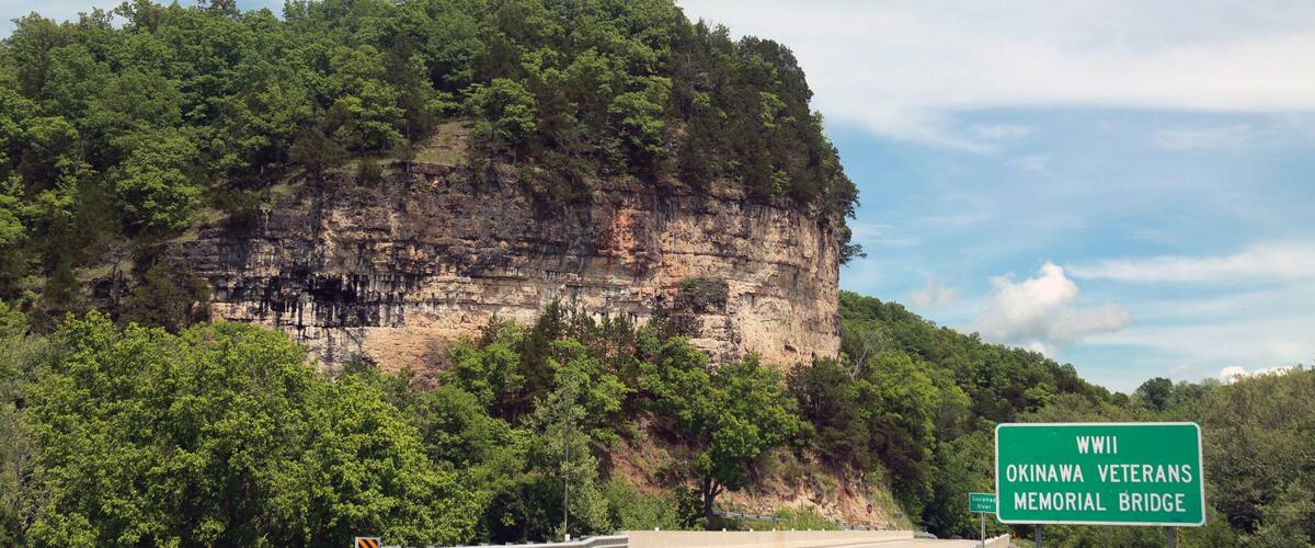 Okinawa Veterans bridge, cliff, woods and white fluffy clouds in Pulaski County, Missouri