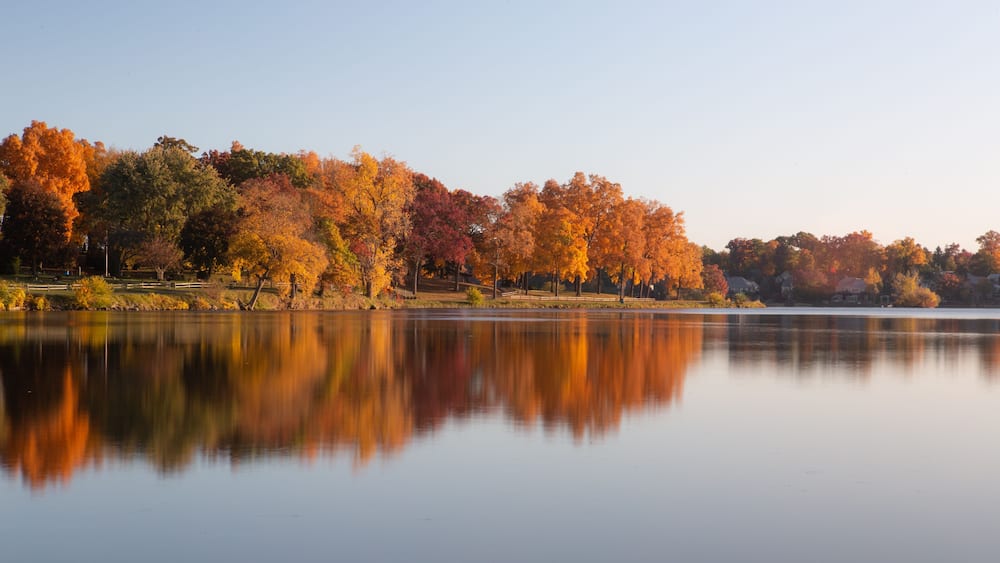 A calm lake with autumn trees reflecting in the water.