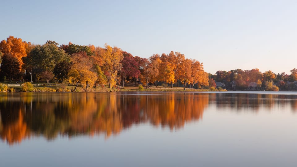 A calm lake with autumn trees reflecting in the water.