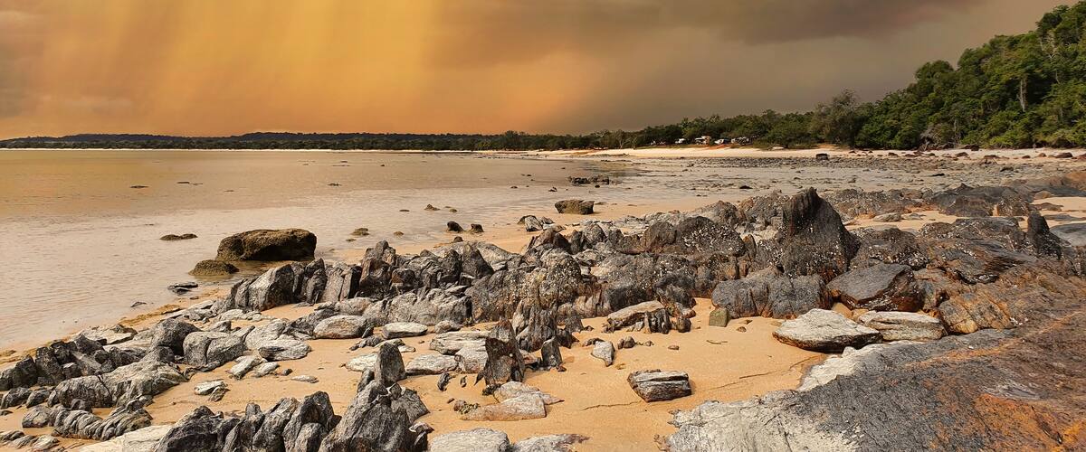 A rocky beach with large boulders and a stormy sky.