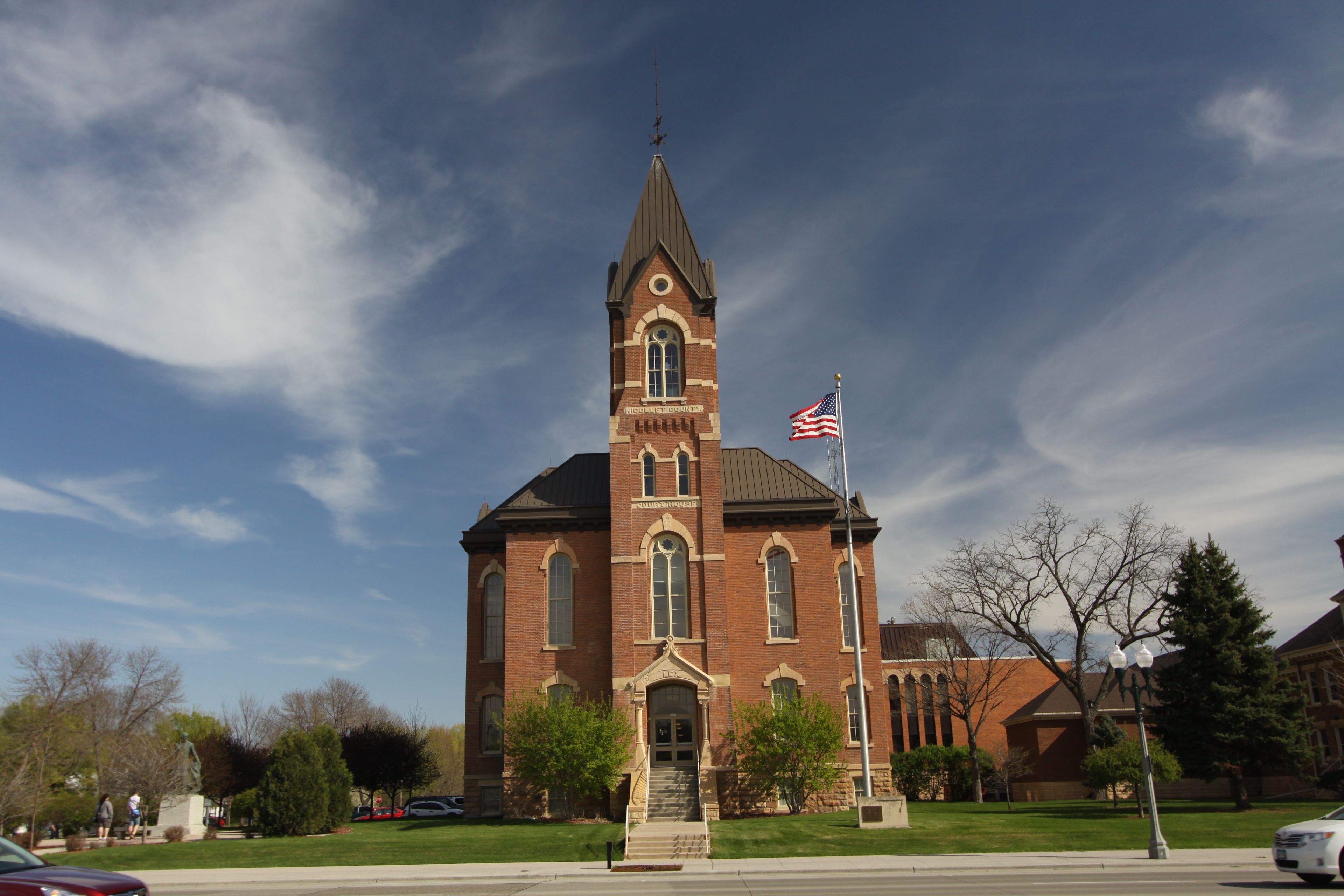 A brick church with a steeple and a flagpole with an American flag.