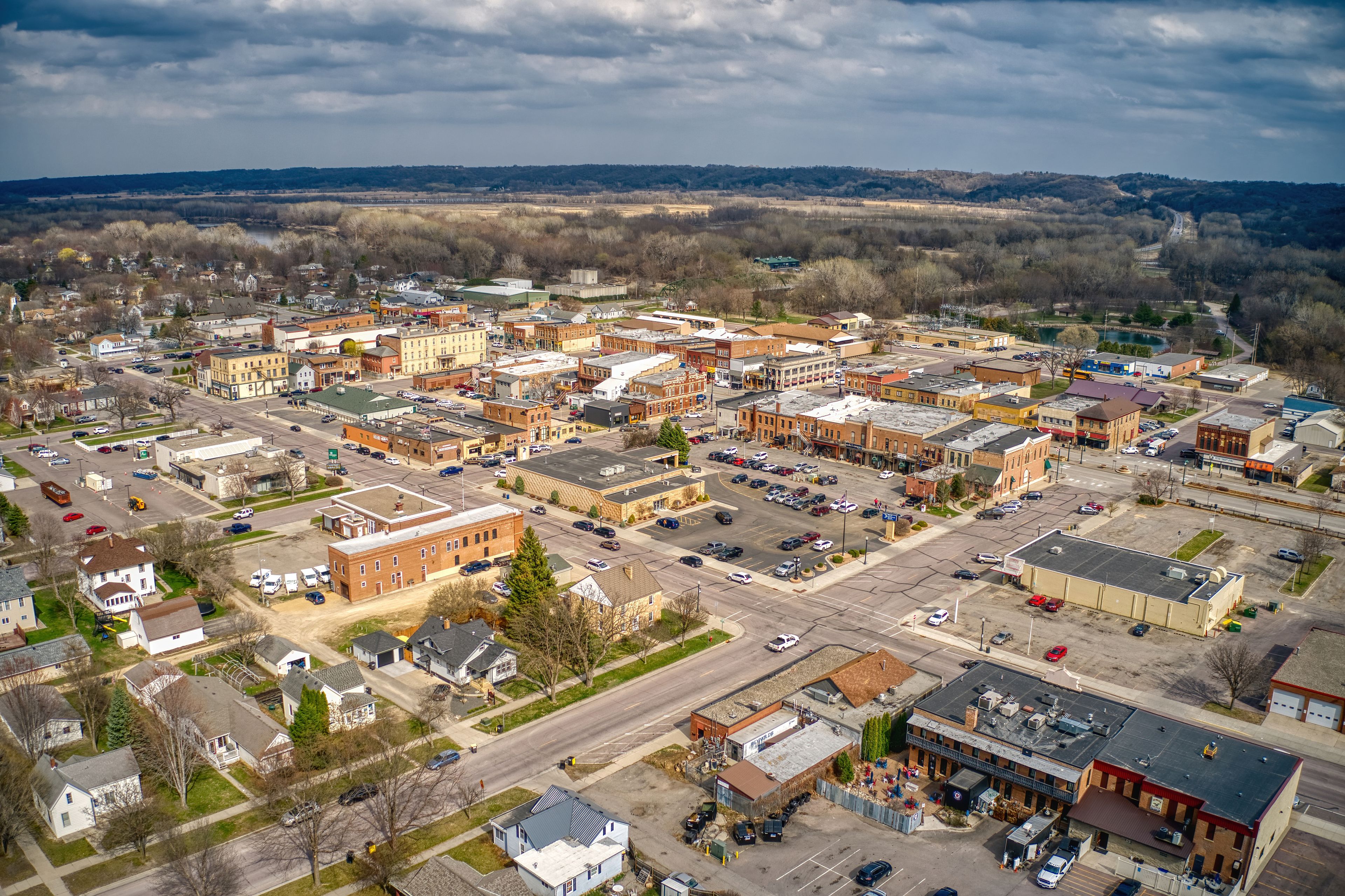 An aerial view of a small town with a mix of commercial and residential buildings, a main street, and surrounding open fields.