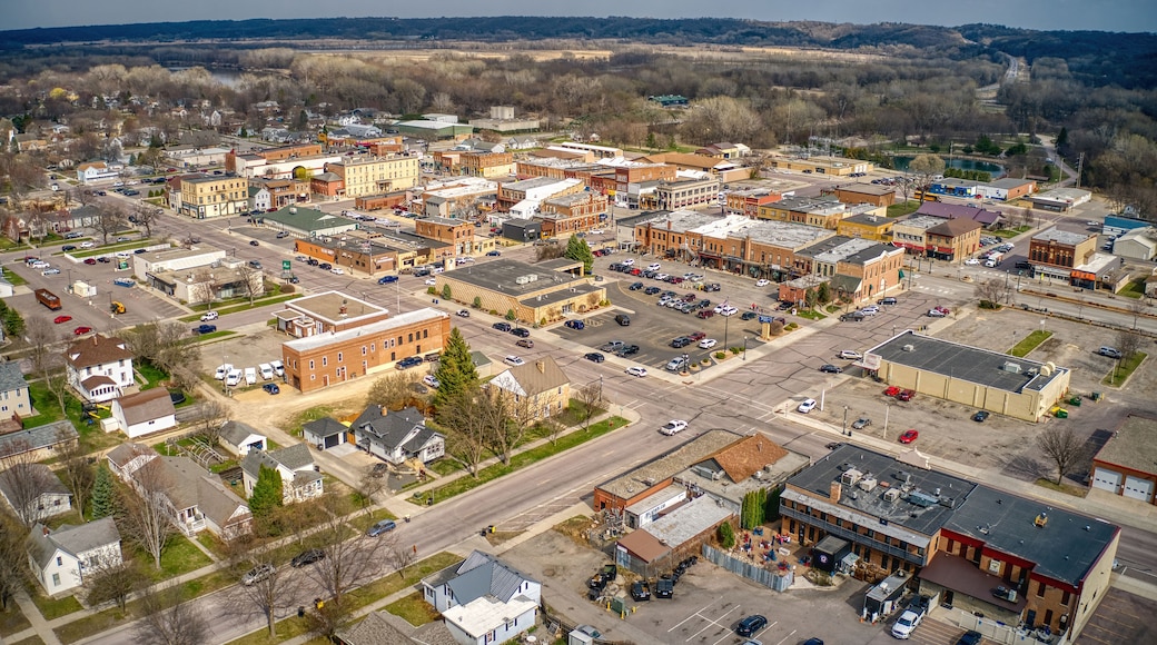 An aerial view of a small town with a mix of commercial and residential buildings, a main street, and surrounding open fields.