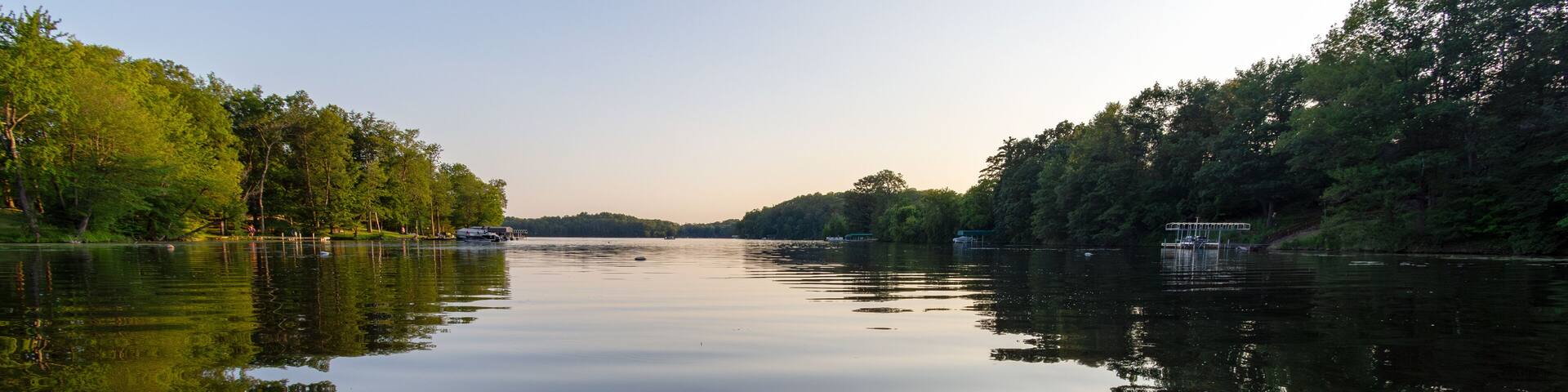 A calm river with trees on both sides and a dock on the right.