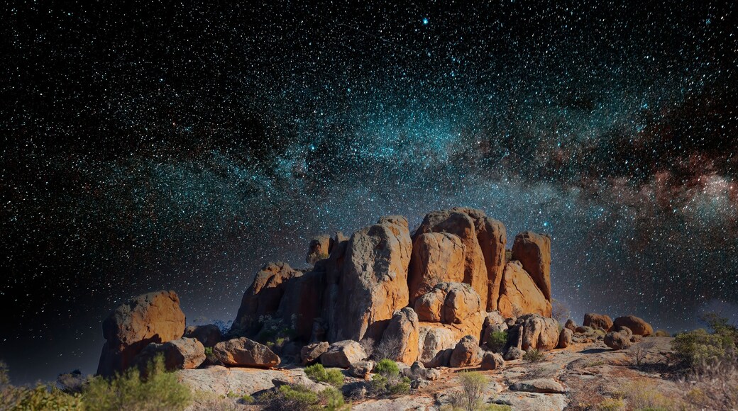Merged image of a rocky outcrop among other rocks in the Australian outback with an image of a starry sky