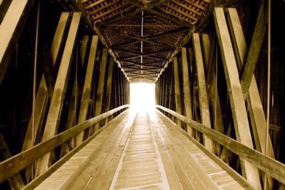 A wooden pedestrian bridge with a central walkway and wooden beams supporting the structure.