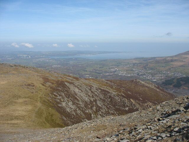 A mountainous landscape with a valley and a body of water in the distance.