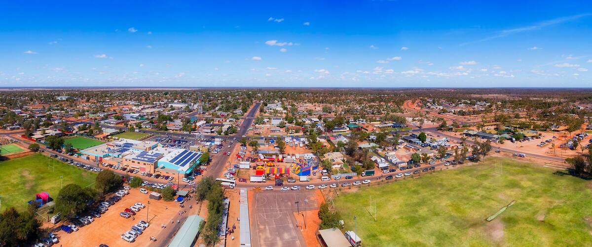 An aerial view of a town with a central road, surrounding residential areas, and a large industrial complex.