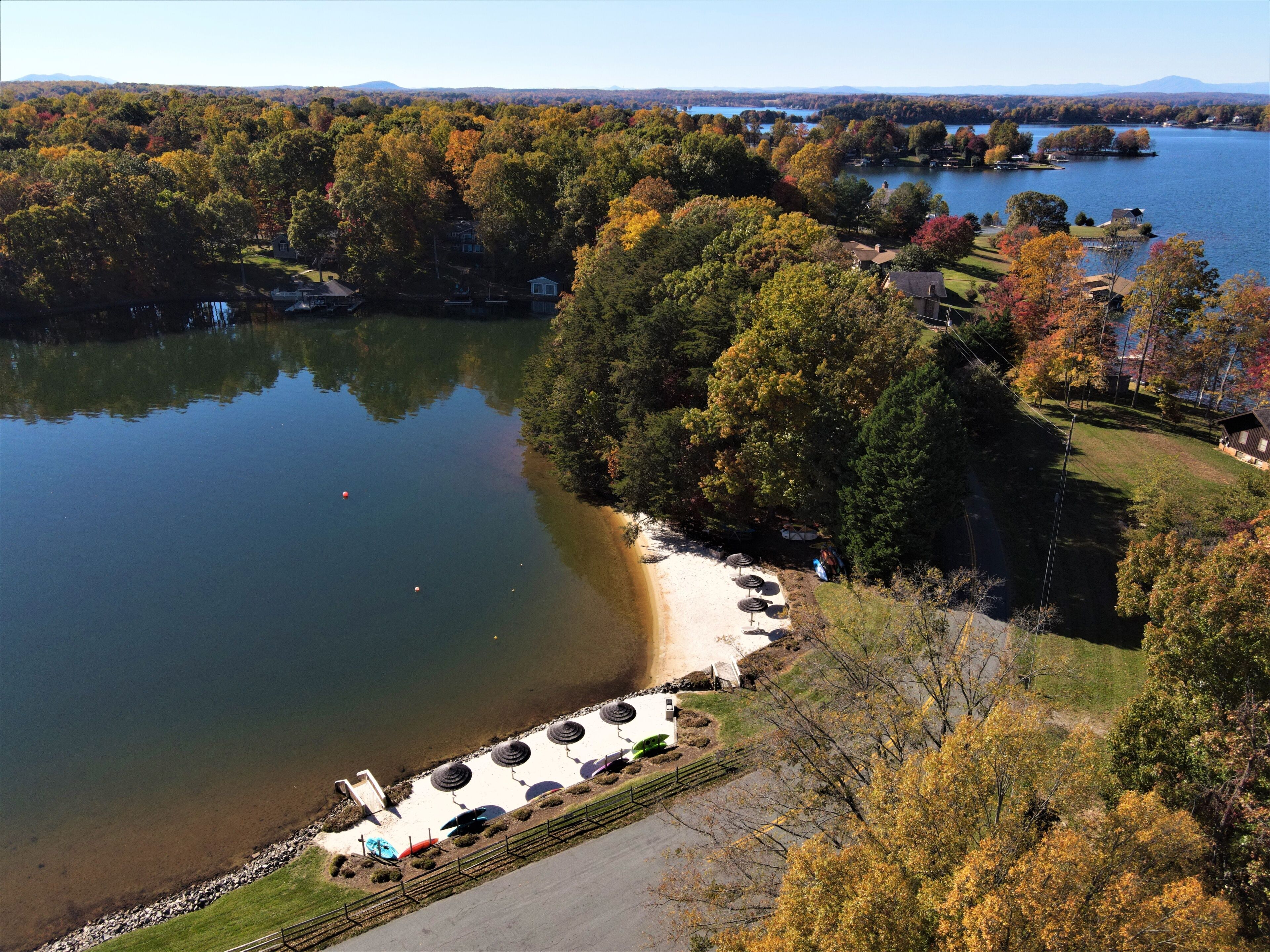 Une vue sur le lac, avec un quai, des tables de pique-nique et des arbres aux couleurs automnales.