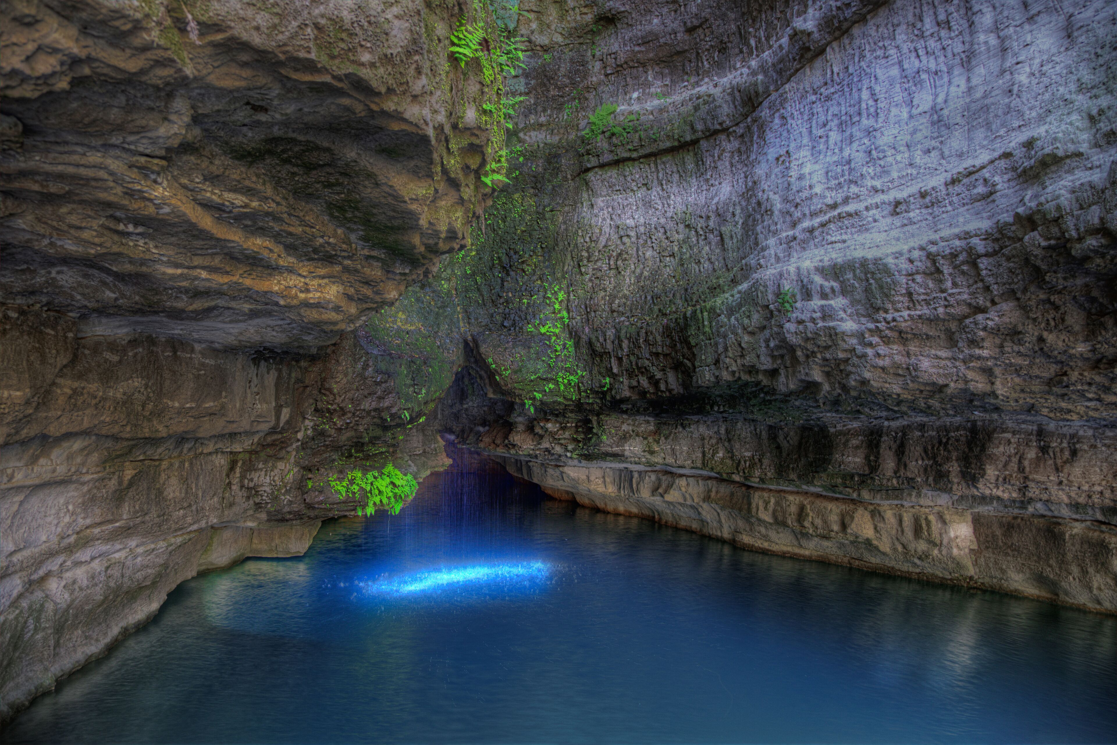A cave with a waterfall and a pool of water.