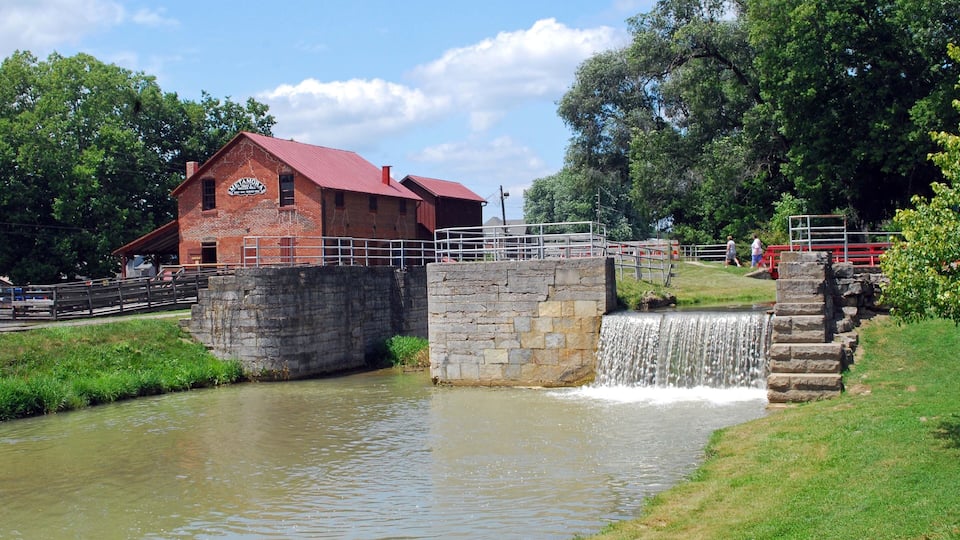 A brick building with a red roof, a stone bridge, and a waterfall.