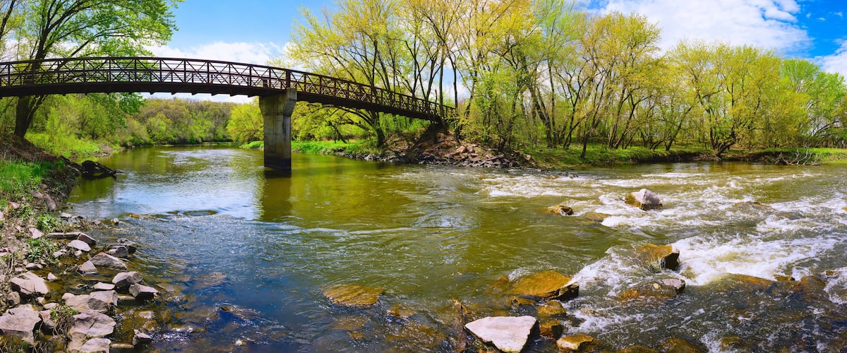 A wooden bridge over a river with rocks and trees.