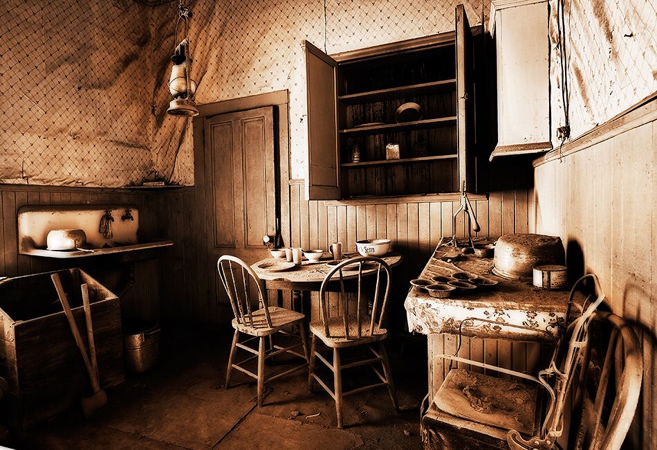 A rustic kitchen with wooden furniture, a hanging light fixture, and a wooden cabinet with shelves.