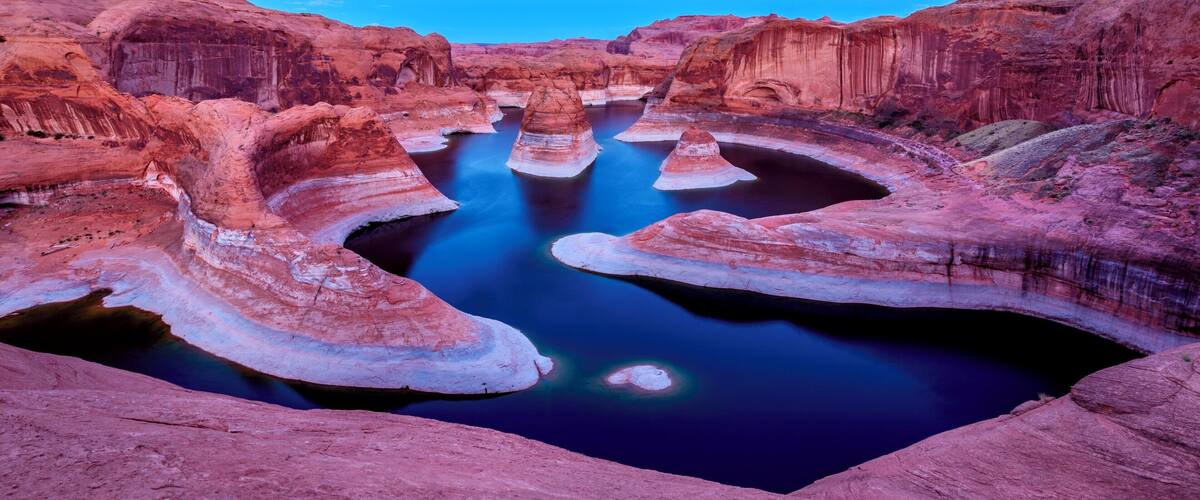 A natural rock formation with a series of caves and a river flowing through it.