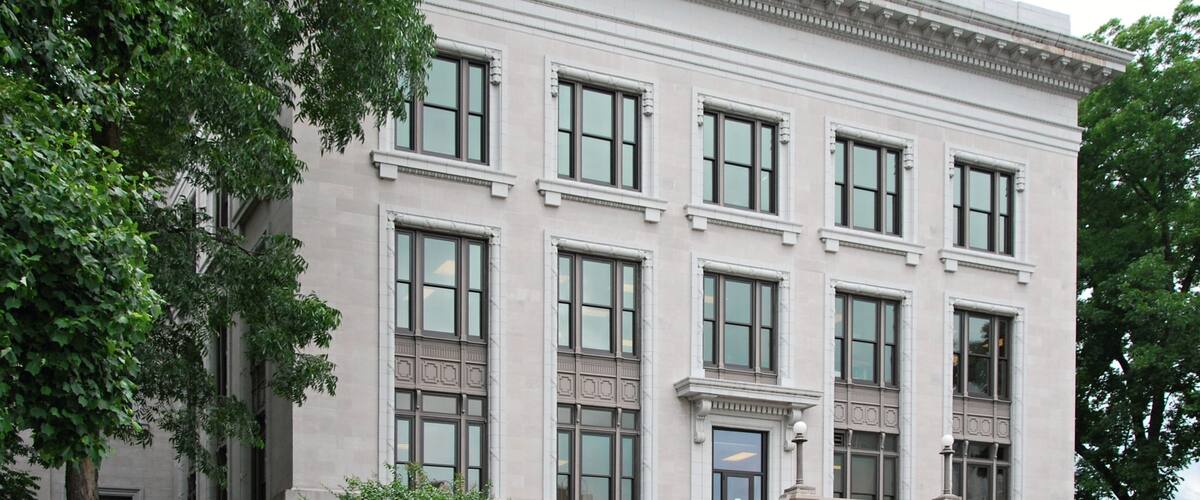 Un edificio grande y blanco con varias ventanas y un toldo rojo.