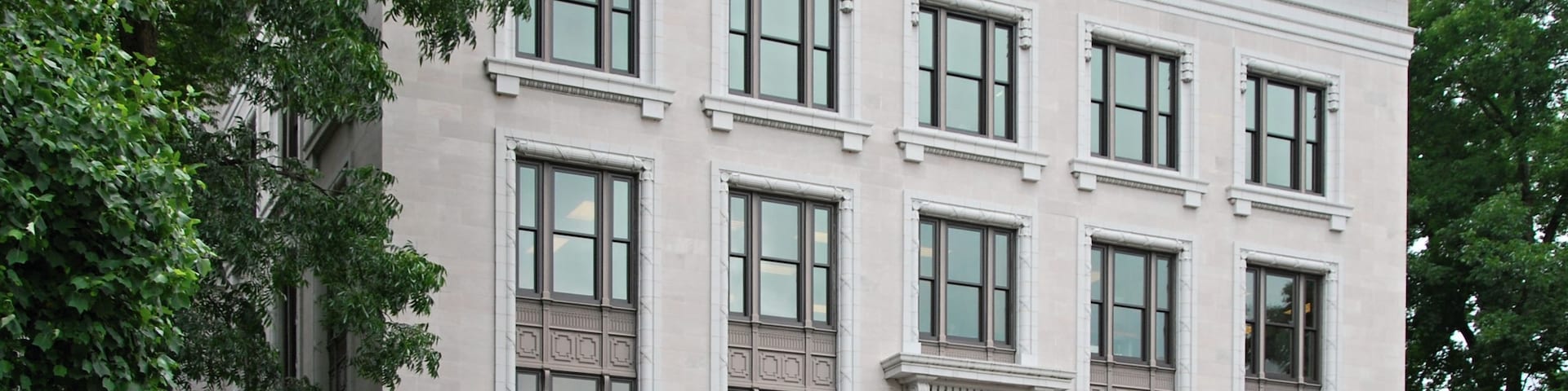 Un edificio grande y blanco con varias ventanas y un toldo rojo.