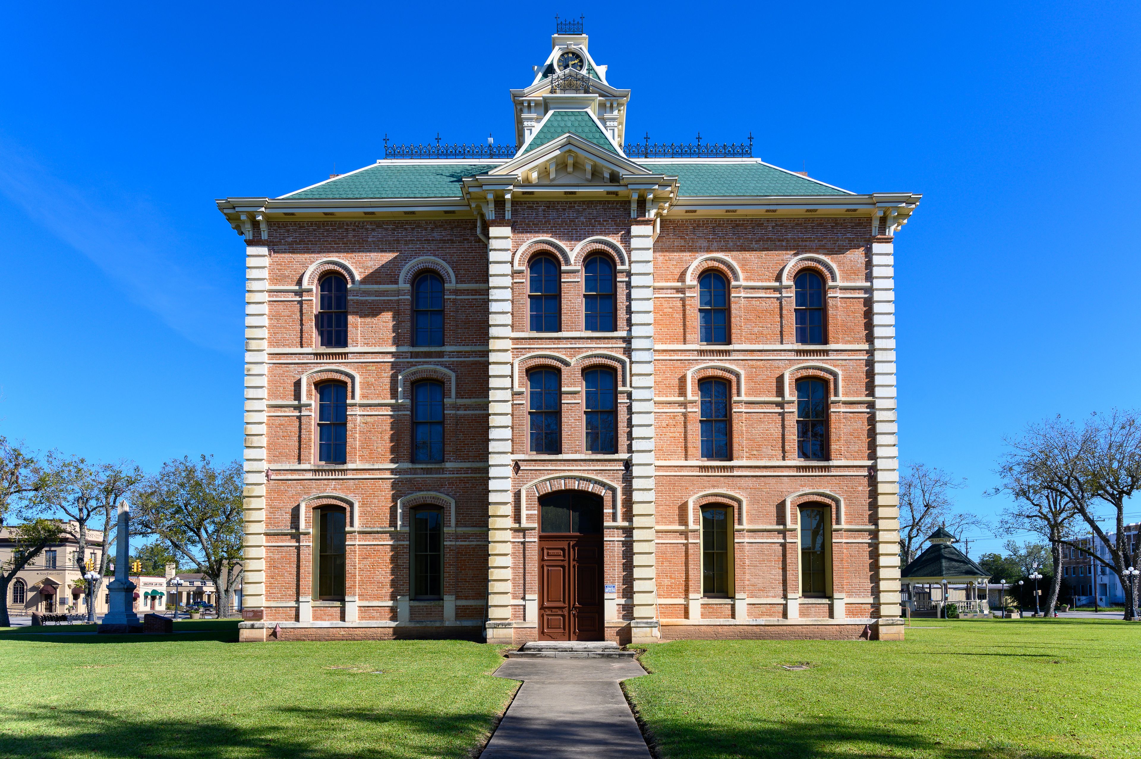A large brick building with a green roof and multiple arched windows.