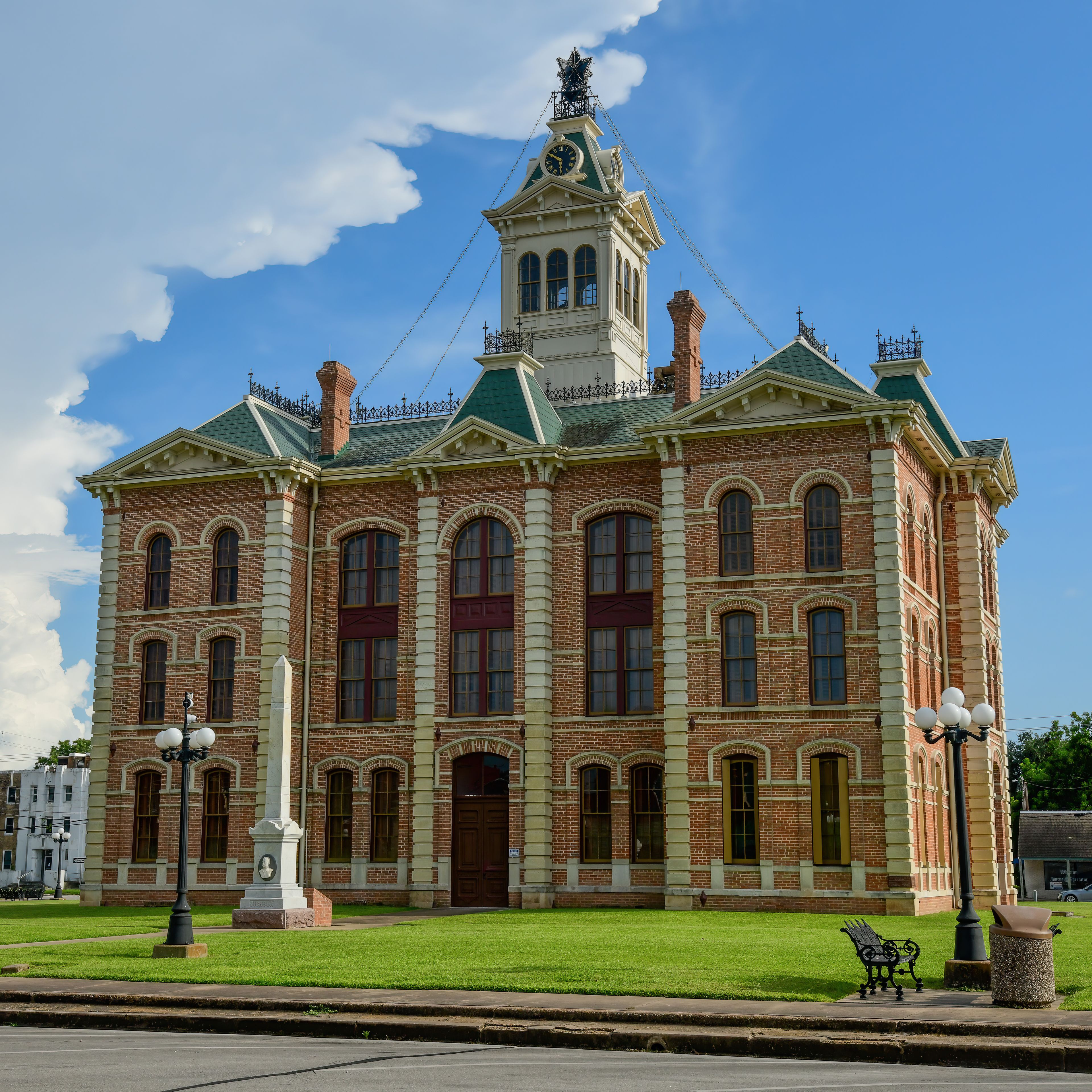 A historic brick building with a clock tower, arched windows, and a green roof.