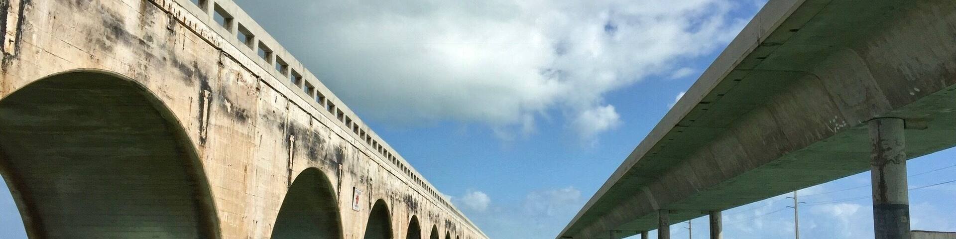 A concrete bridge over water with multiple arches and a clear sky.