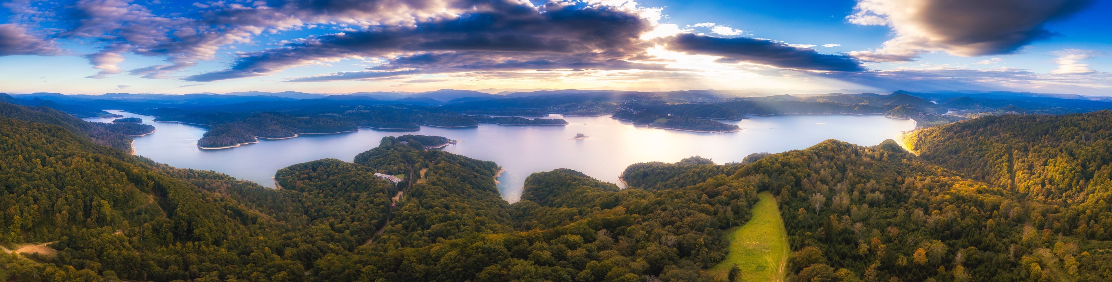 A panoramic view of a lake surrounded by forested hills.