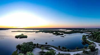 Un atardecer sobre un lago tranquilo con islas y un puente.
