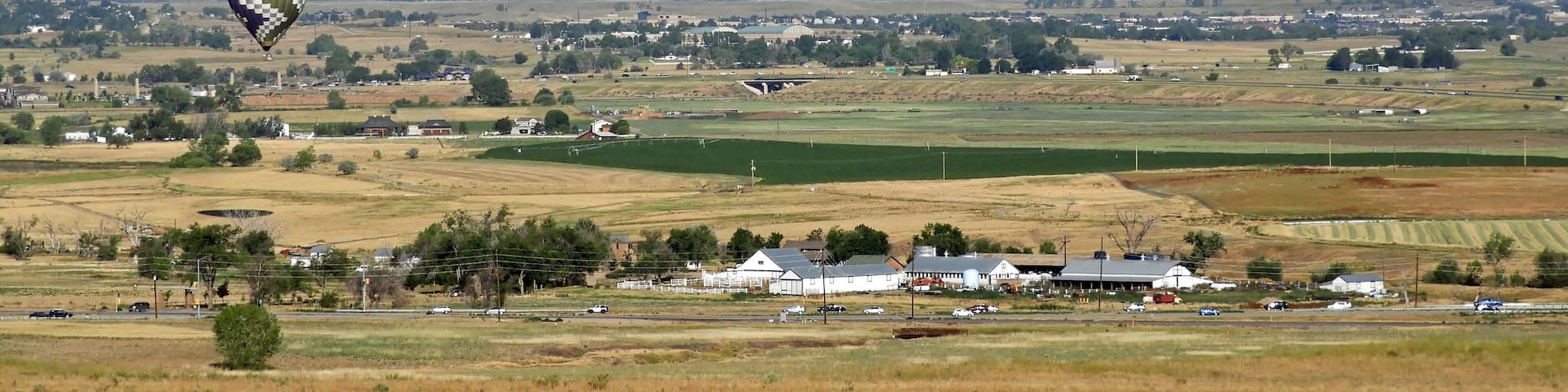 early morning balloons touring over the foothills of boulder county on a sunny summer day, with a backdrop of the front range, as seen from broomfield, colorado