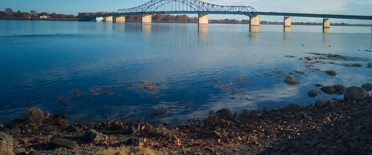 Historic blue and white arch truss bridge over the Columbia River with blue skies and clouds on a sunny morning in Kennewick-Pasco Washington