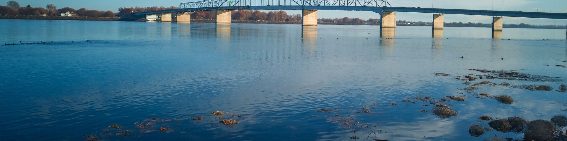 Historic blue and white arch truss bridge over the Columbia River with blue skies and clouds on a sunny morning in Kennewick-Pasco Washington