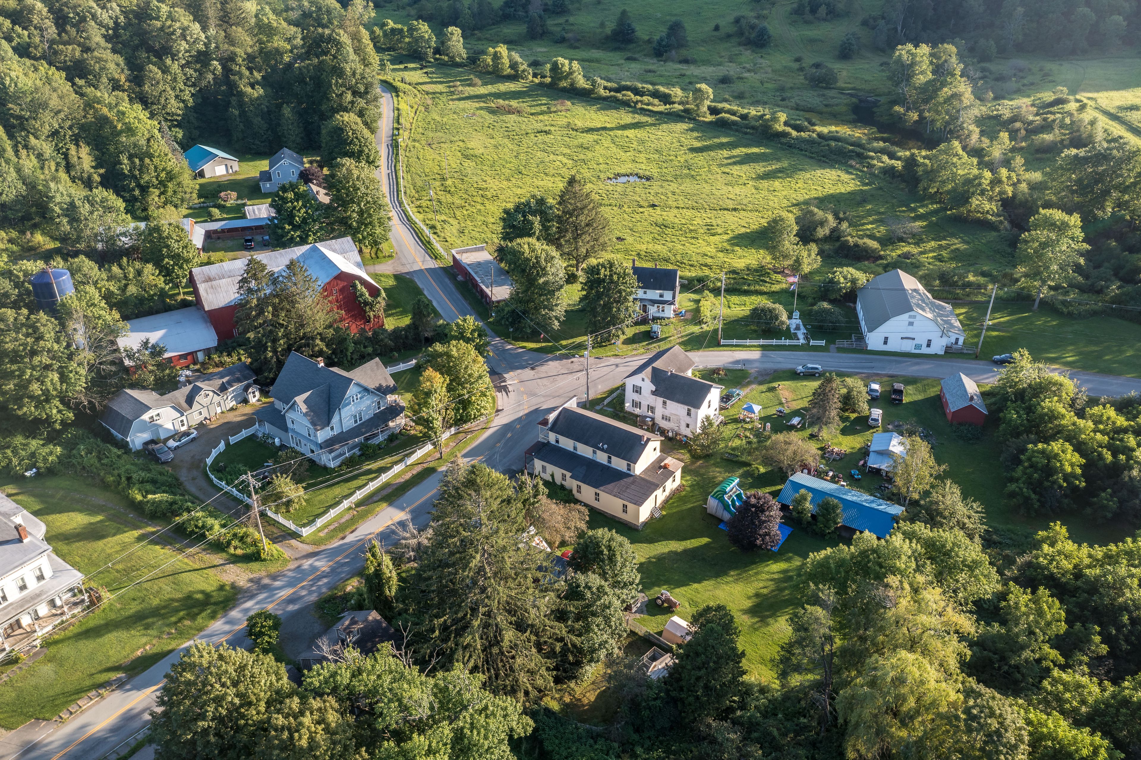 Vista aérea de una comunidad rural con casas, caminos y vegetación circundante.