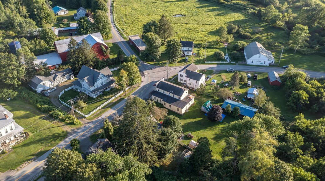 Vista aérea de una comunidad rural con casas, caminos y vegetación circundante.
