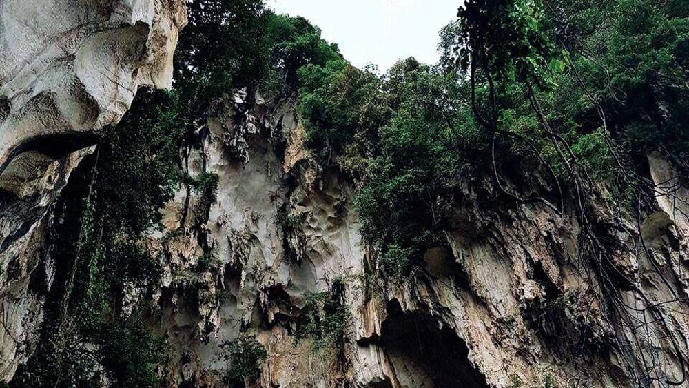 A large cave opening with a group of people at the entrance.