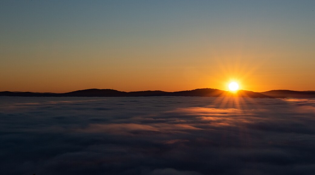 Un lever de soleil sur une mer de nuages, le soleil Ă©tant visible au-dessus de lâhorizon.