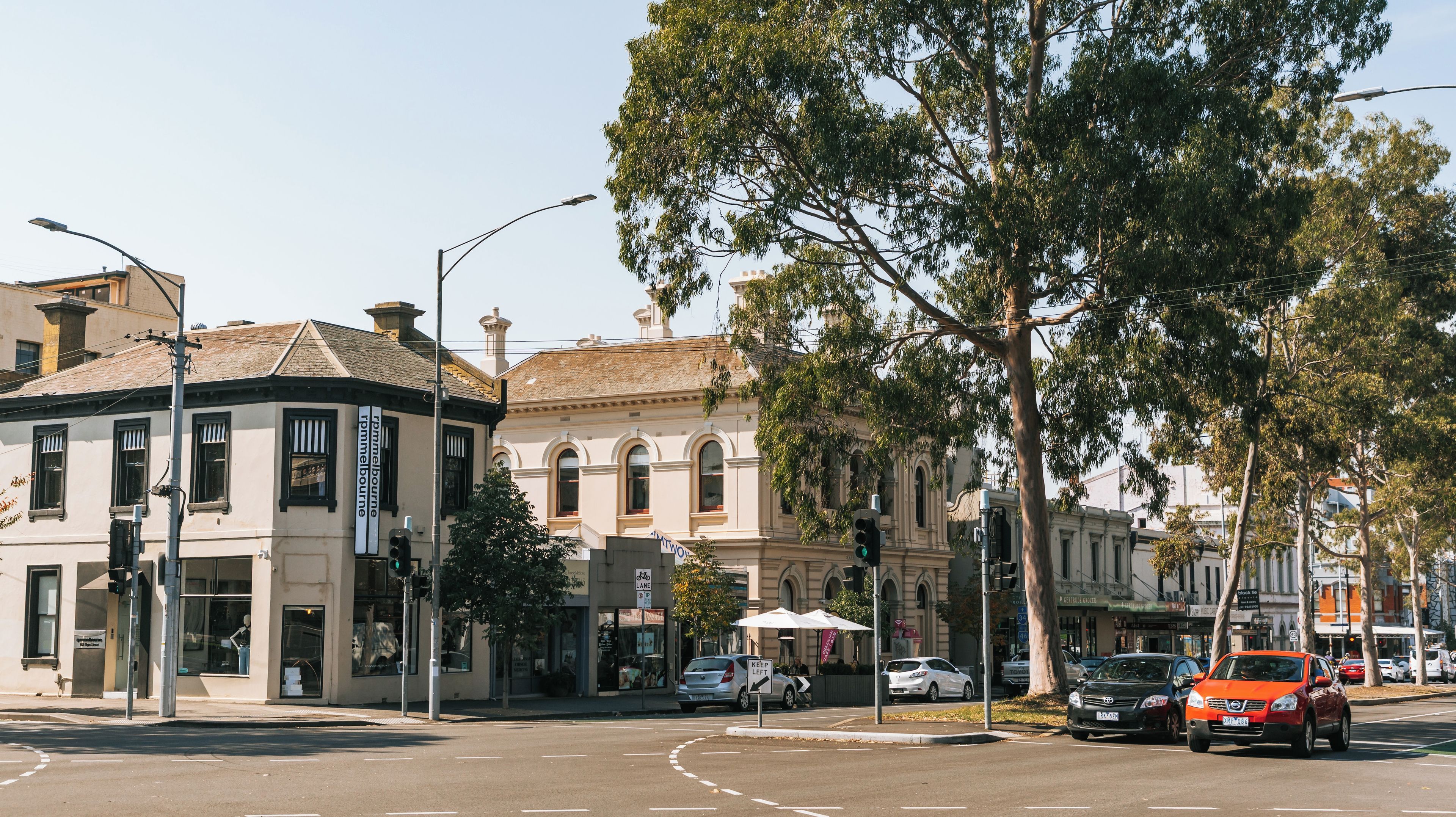 A street intersection with vintage buildings, a traffic light, and parked cars.