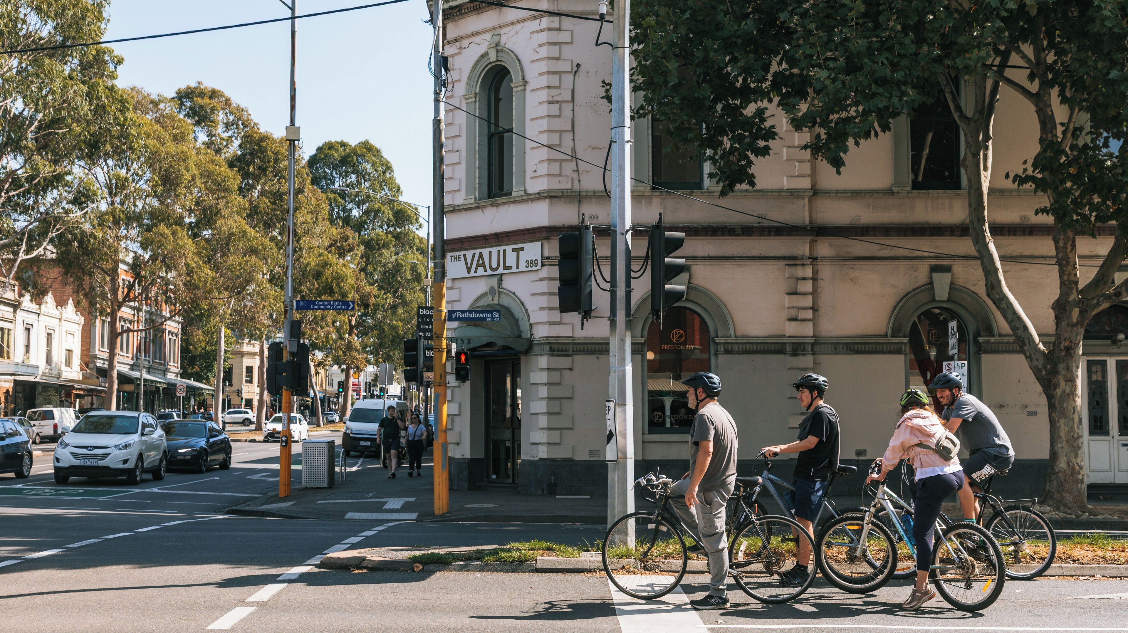 A street scene with cyclists, a building labeled 'The Vault 389,' and a sign for 'City Hall.'