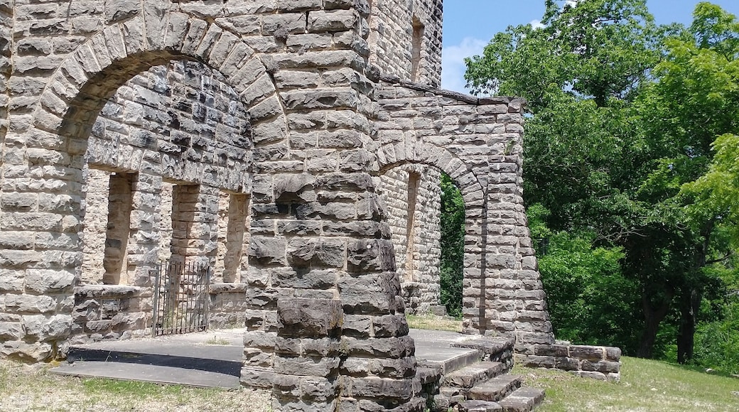An ancient stone structure with arched doorways and a tower.