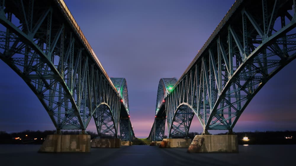 A large steel bridge with two main arches and a road in the center.