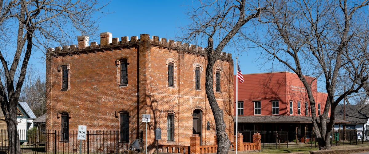 A historic brick building with arched windows and a flagpole.
