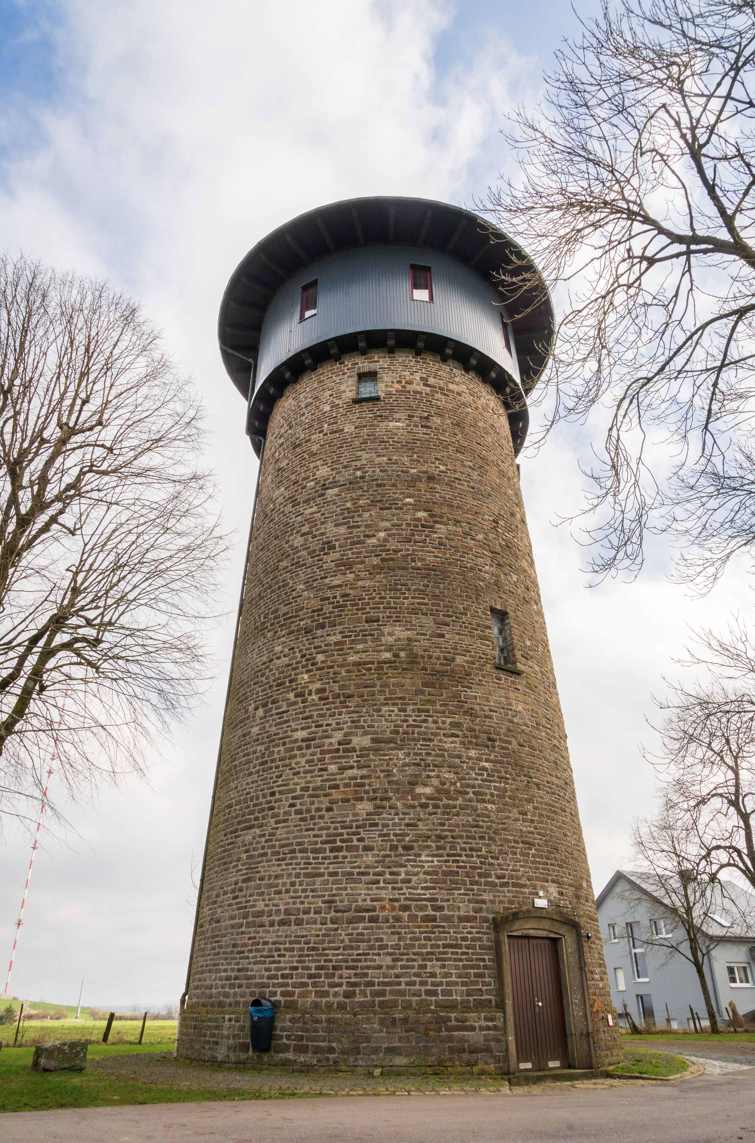 A tall brick tower with a cylindrical shape and a conical roof.