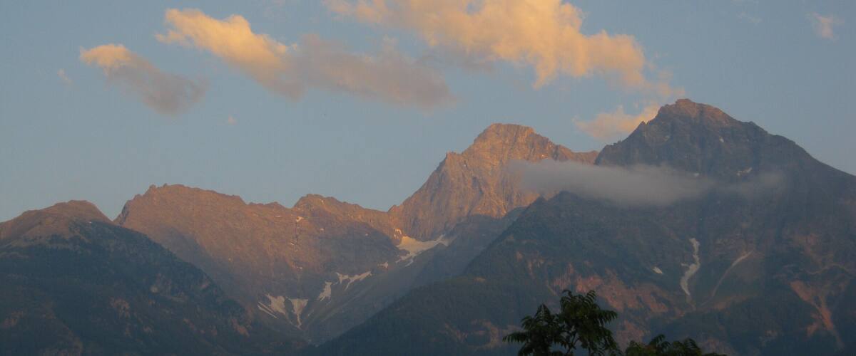 A mountain range with snow-capped peaks and a forested foreground.