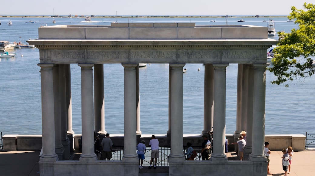 A neoclassical monument with columns overlooking a body of water with boats.