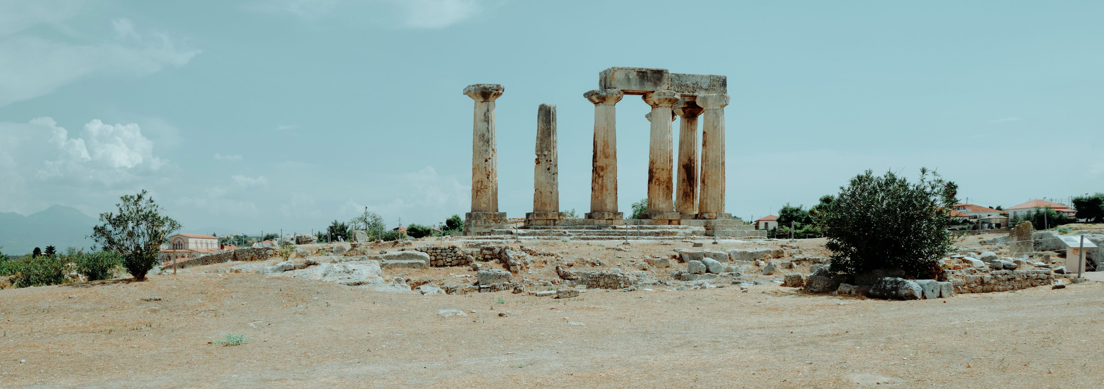 Ancient stone columns on a hill with a clear sky.