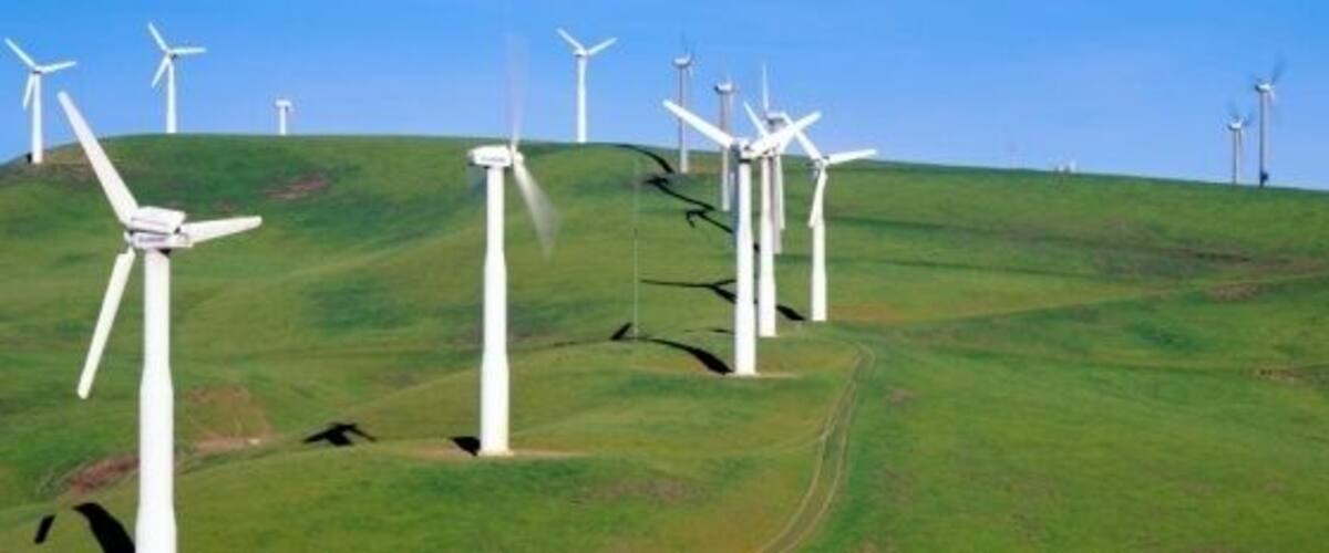 A landscape with multiple wind turbines on a grassy hill.