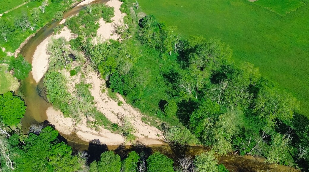 Panorama aerial view sandy river bank Lick Fork Gasconade River running water moving to lower level in Wright County, Mansfield, Missouri, large grassy meadow vacant farmland, rural countryside