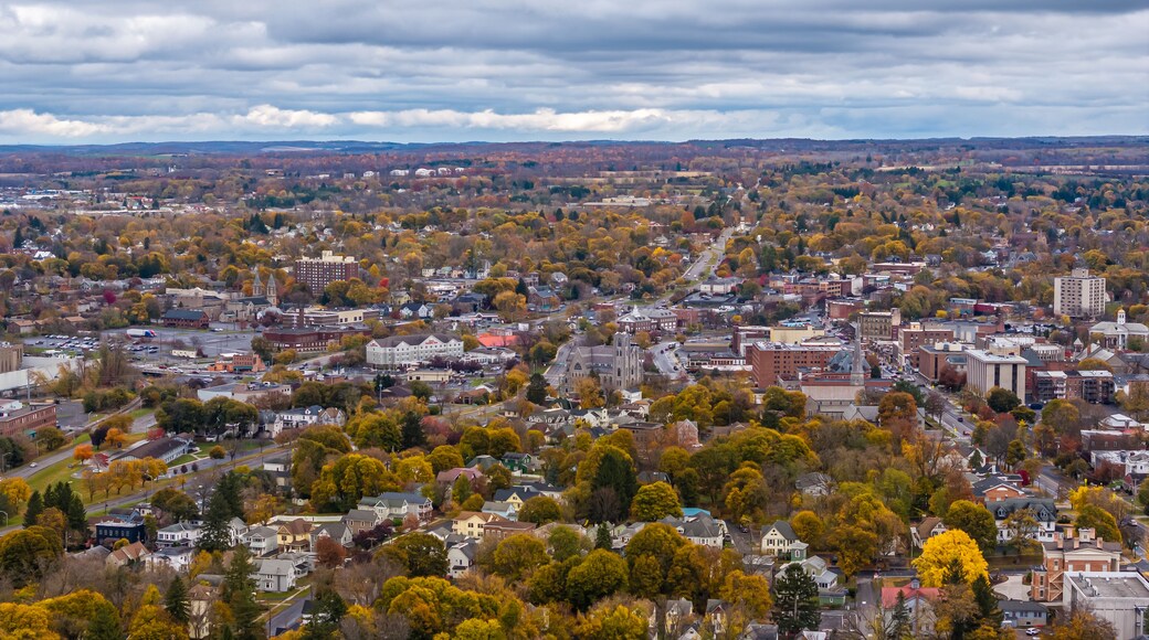 A cityscape with autumn foliage, a prominent church, and a distant mountain range.